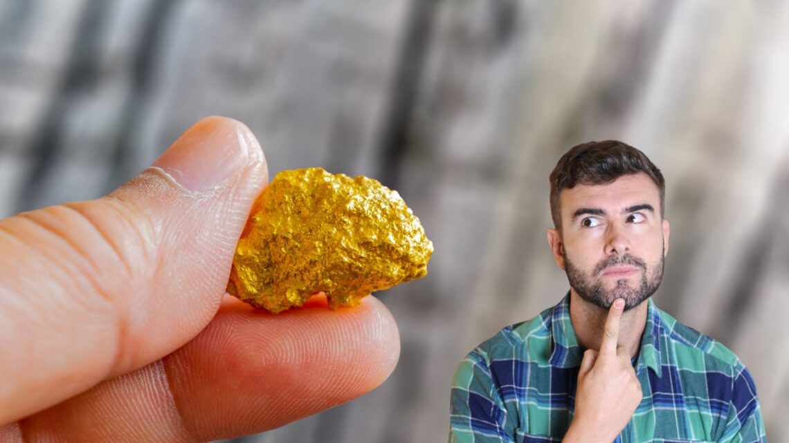 Un homme semble pensif en observant une pépite d'or tenue au premier plan pour déterminer son authenticité.
